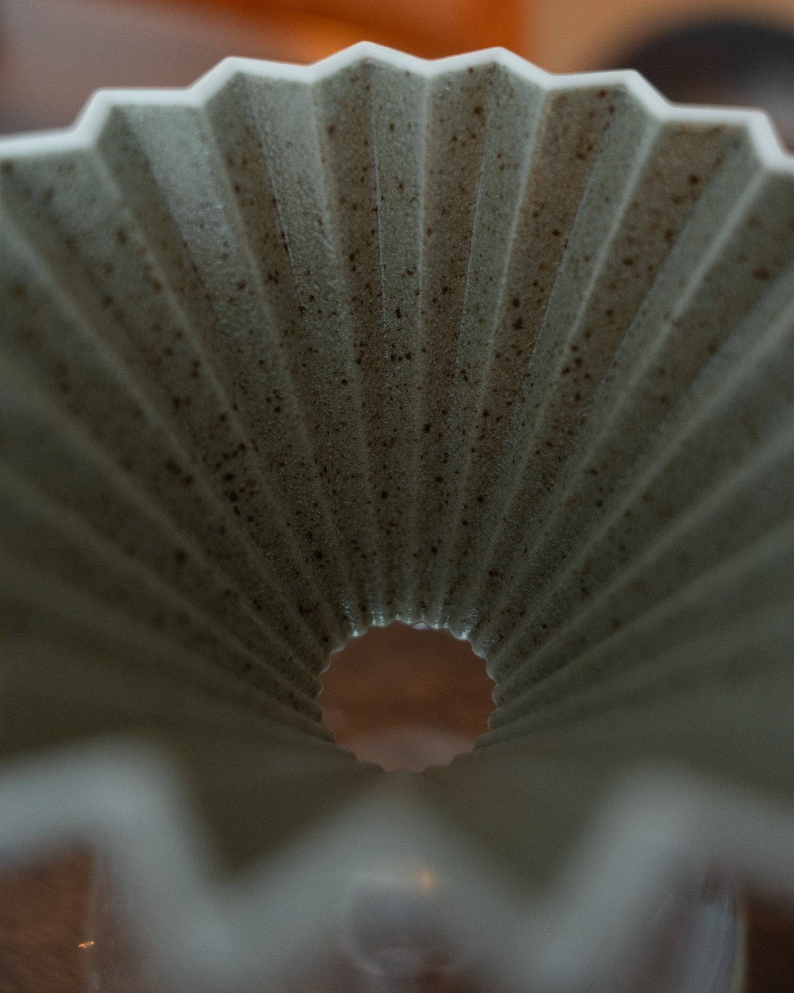 Close-up view of Origami Dripper Mikage, showcasing its unique fan-like shape and textured sand-glazed surface. The ceramic coffee dripper&