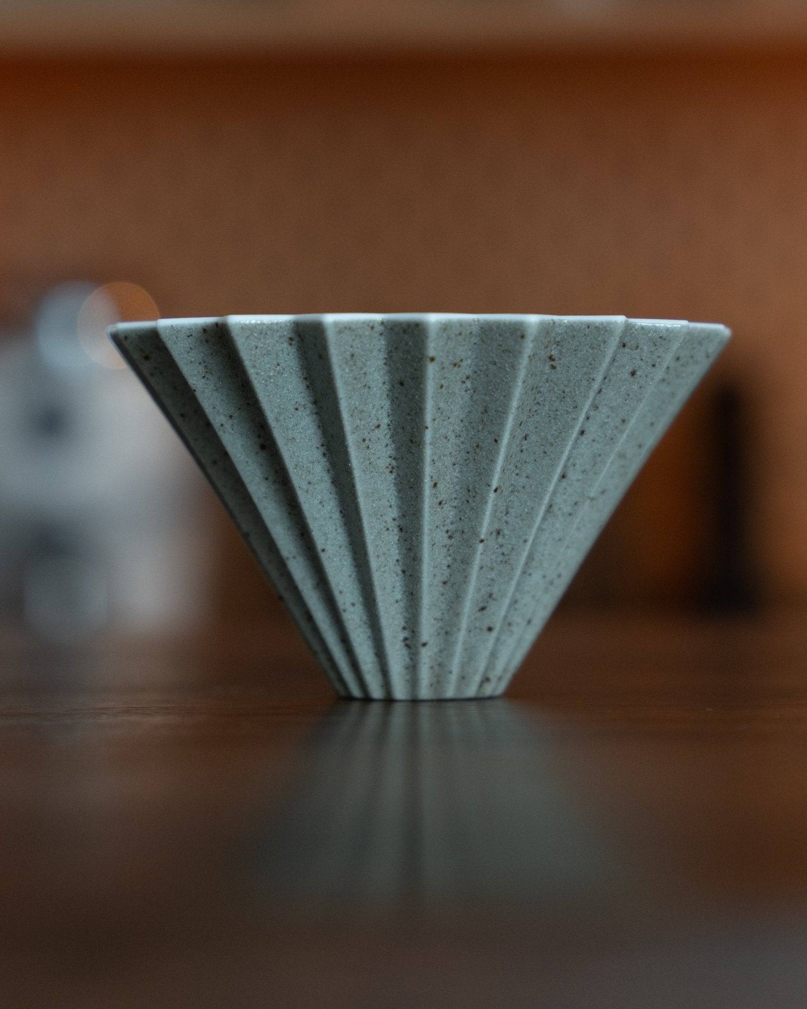 Origami Dripper Mikage limited edition coffee filter in light blue ceramic with unique sand glaze texture, showcasing Japanese wabi-sabi aesthetics and traditional craftsmanship on a wooden surface
