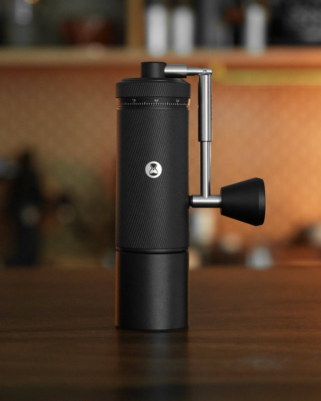 Timemore Chestnut S3 manual coffee grinder with external adjustment dial, sleek black design, foldable handle, and precision grinding mechanism, displayed on wooden countertop in kitchen setting