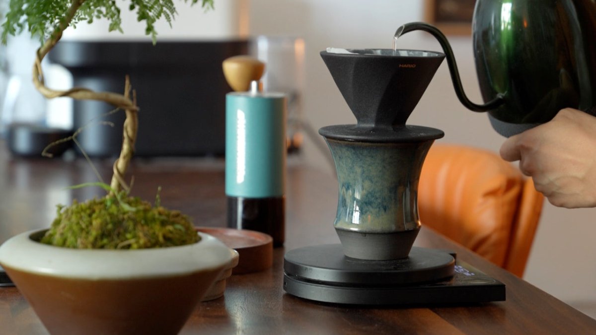 手沖濾杯直接架在 Coffee Stage Sharing Cup L Size 上，咖啡壺正在注水沖煮