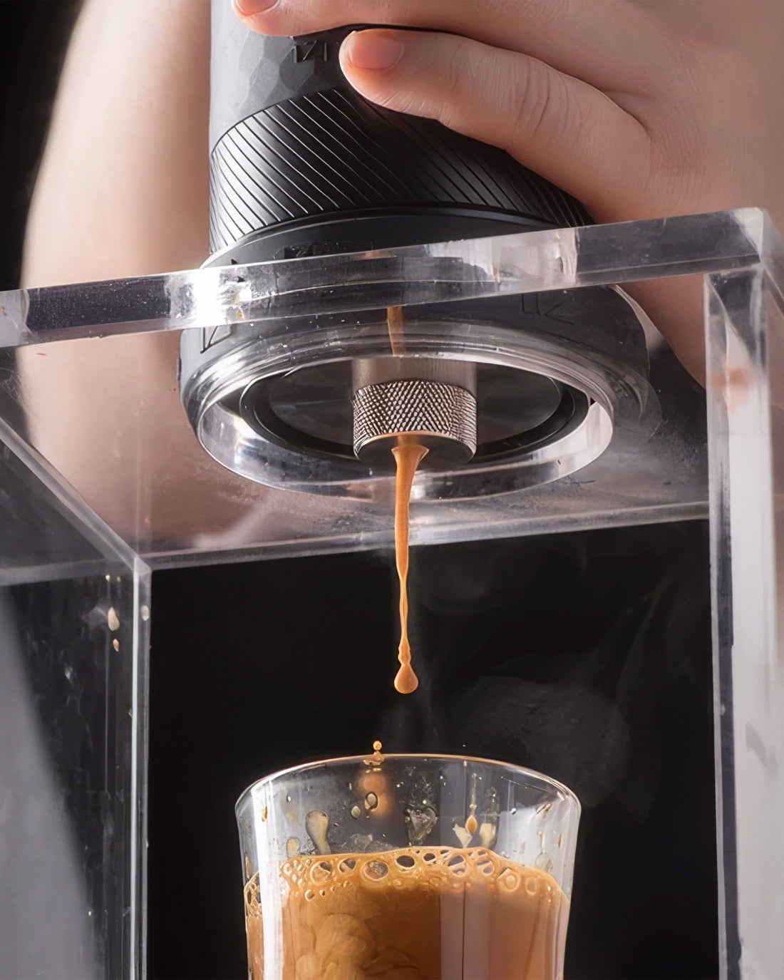 1Zpresso Y3 metal edition hand-press espresso machine in action, showing coffee extraction process with golden crema dripping into a transparent glass, highlighting portability and high-quality brew capabilities