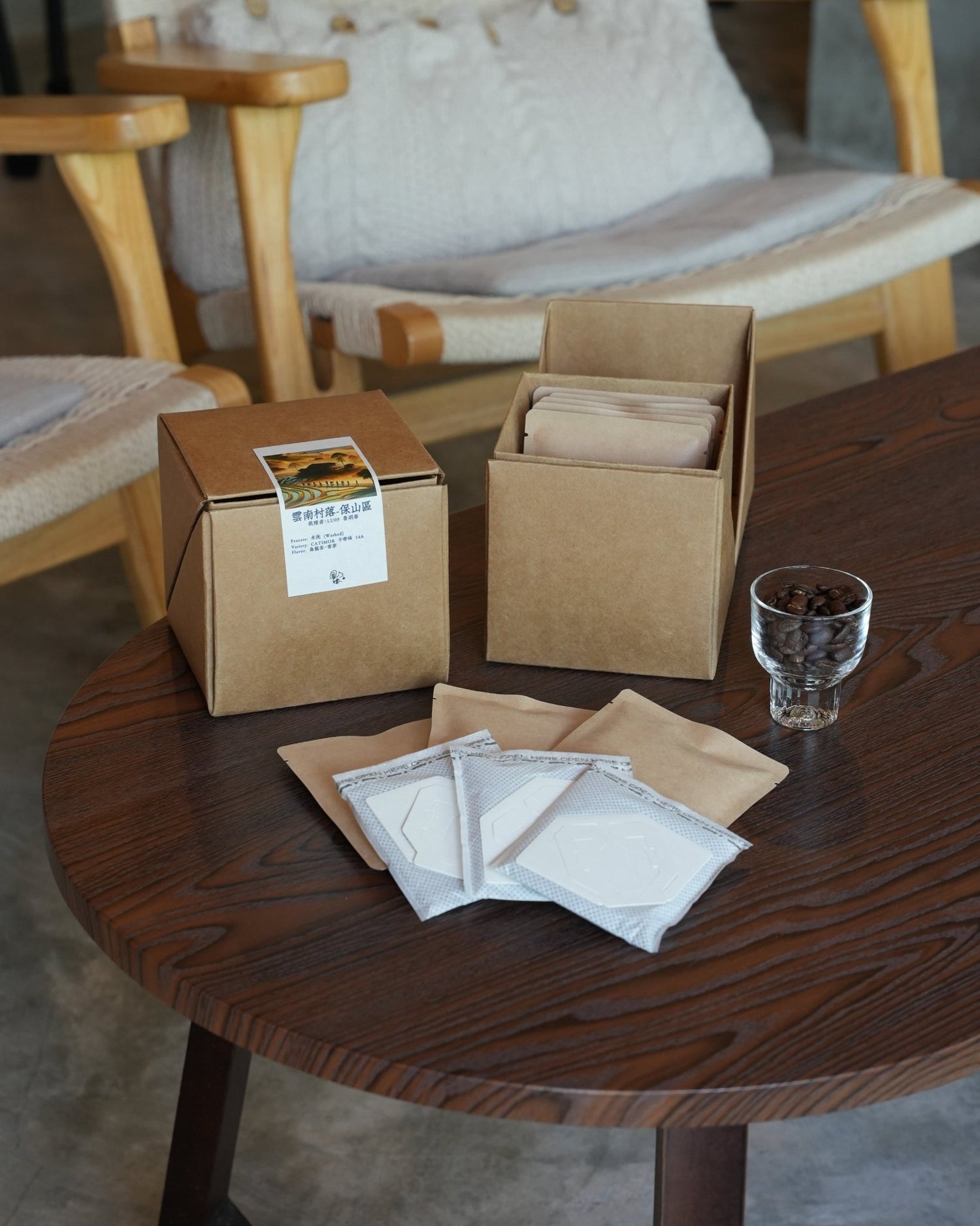 Coffee product packaging on wooden table with boxes, filter bags, and a glass of coffee beans, showcasing Yunnan CATIMOR 14A washed coffee from Sip Coffee brand