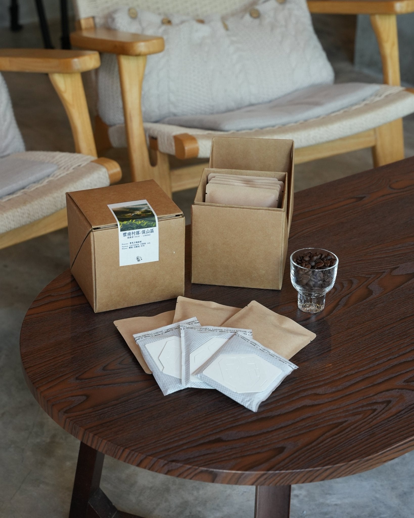 Yunnan Catimor 14A coffee packaging on wooden table with drip bags and glass of coffee beans, showcasing eco-friendly packaging and brewing options for Sip Coffee&