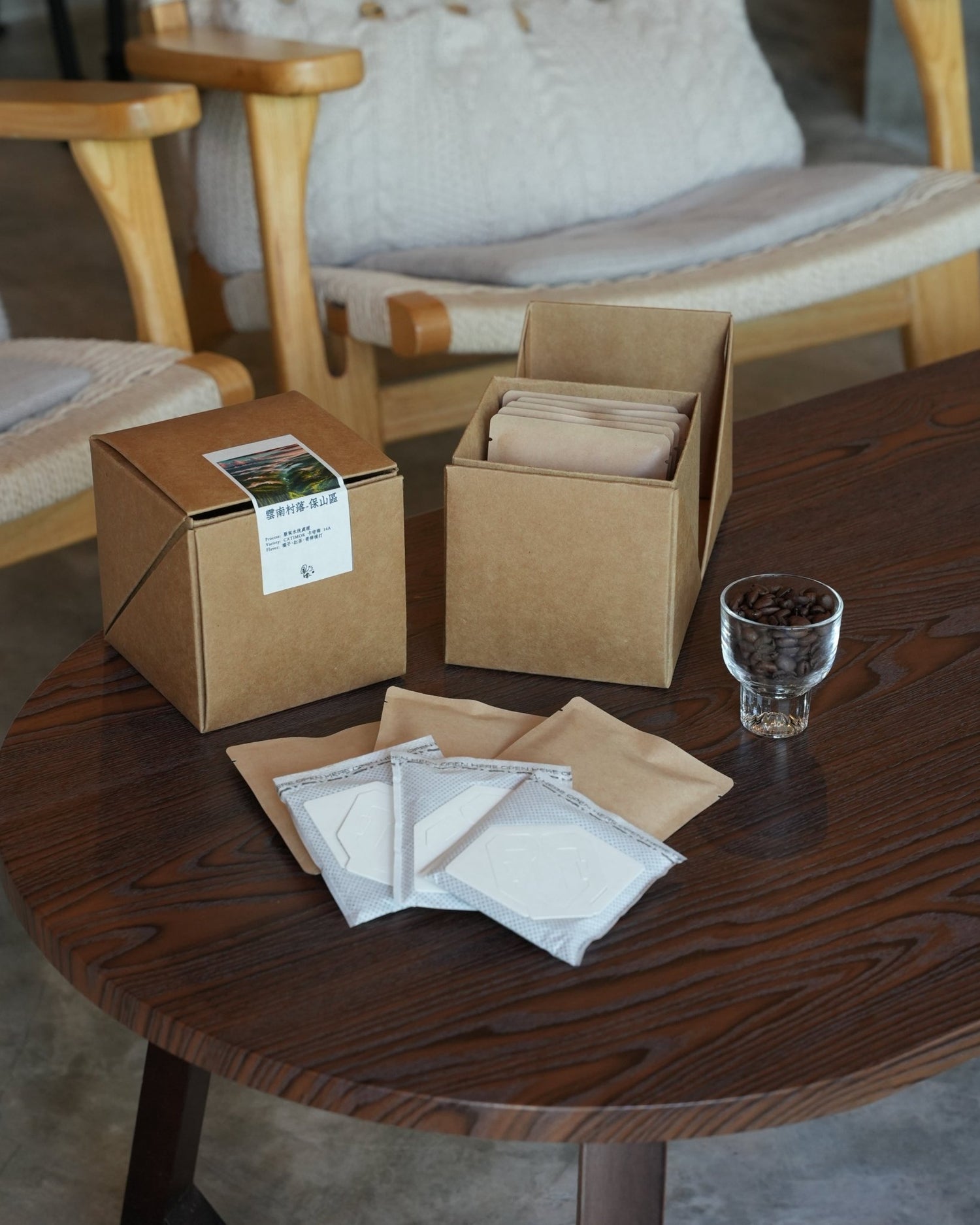 Coffee product display on wooden table with packaging boxes, drip bags, and a glass of coffee beans, showcasing Yunnan CATIMOR 14A Anaerobic Washed coffee from Sip Coffee brand