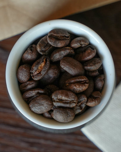 Freshly roasted Yunnan CATIMOR 14A coffee beans from Baoshan region in a white ceramic cup, showcasing rich brown color and distinct bean shapes