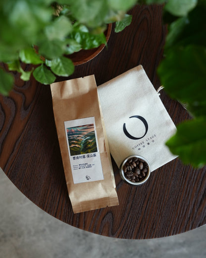 Coffee packaging from Yunnan village displayed on wooden table with coffee beans and plant leaves, showcasing Sip Coffee&