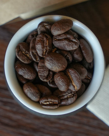 Freshly roasted Yunnan CATIMOR 14A coffee beans in a white ceramic bowl, showcasing the light roast and unique characteristics of this specialty coffee from Baoshan region.