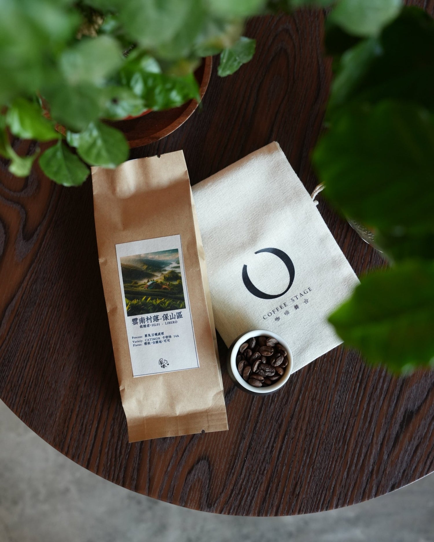 Coffee packaging and roasted beans on wooden surface with green plant leaves in foreground, showcasing Yunnan coffee product from Sip Coffee brand