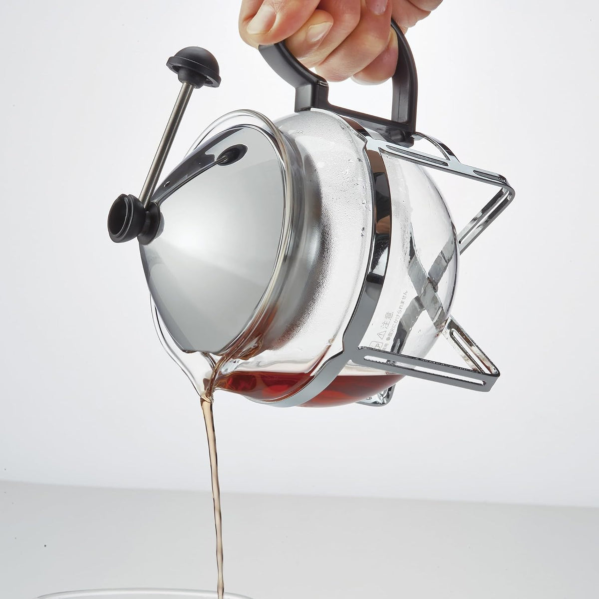 手持金屬框架茶壺倒出茶湯