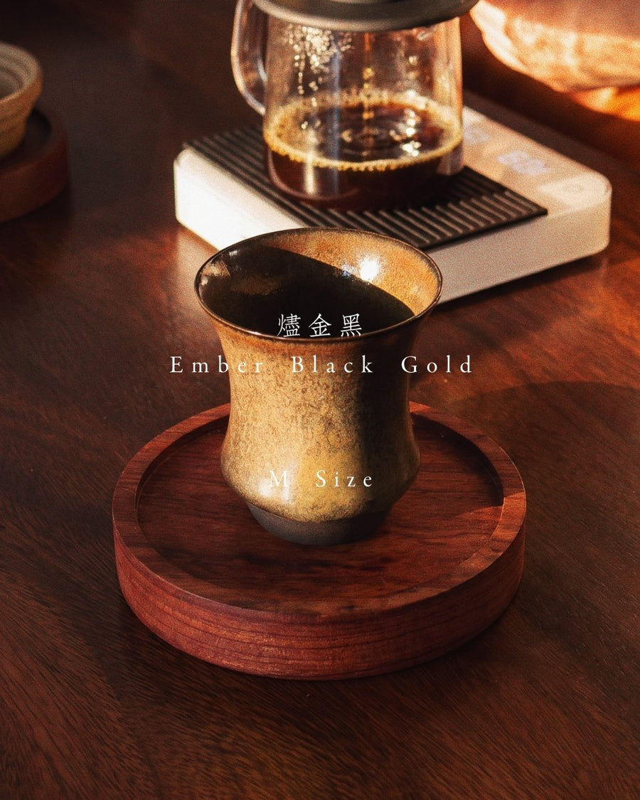 Sharing Cup M Size in Ember Black Gold on a wooden tray, with the body shifting from a dark rim to golden brown and a clearly defined waist