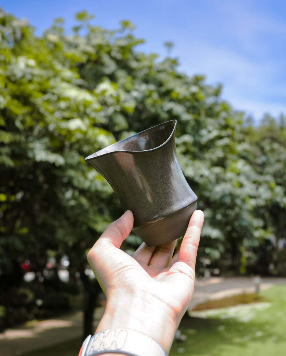 A Sharing Cup held outdoors, showing the waisted body and flared rim from the side