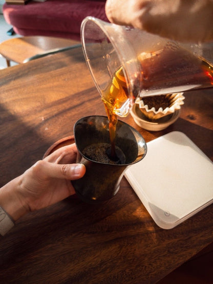 咖啡由分享壺倒入 Coffee Stage Sharing Cup Alpha Size 燼金黑，展示凹入式杯口與日常使用