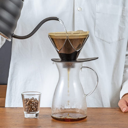 Shared HARIO V60 MUGEN image for the white ceramic and transparent black AS resin models: V60 MUGEN brewing scene with coffee flowing into a glass server; the kettle and server are scene props.