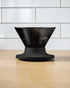HARIO V60 NEO 01 black pour-over coffee dripper on a Japanese-style coffee brewing counter, cover image candidate