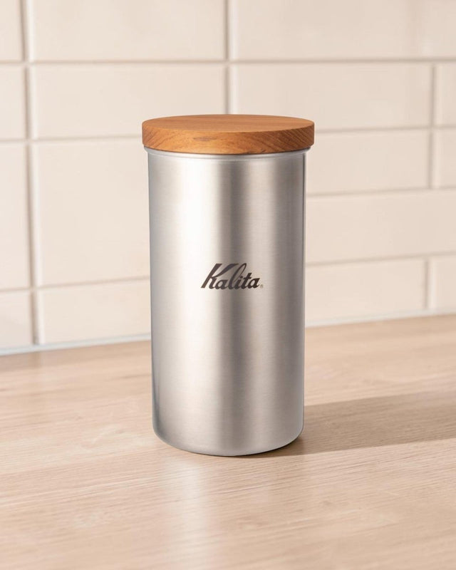 Kalita for Outdoors stainless steel coffee bean canister on a bright kitchen countertop