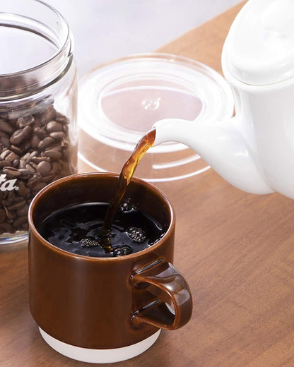 White Kalita HASAMI &amp; Kalita HA coffee server pouring coffee into a brown mug