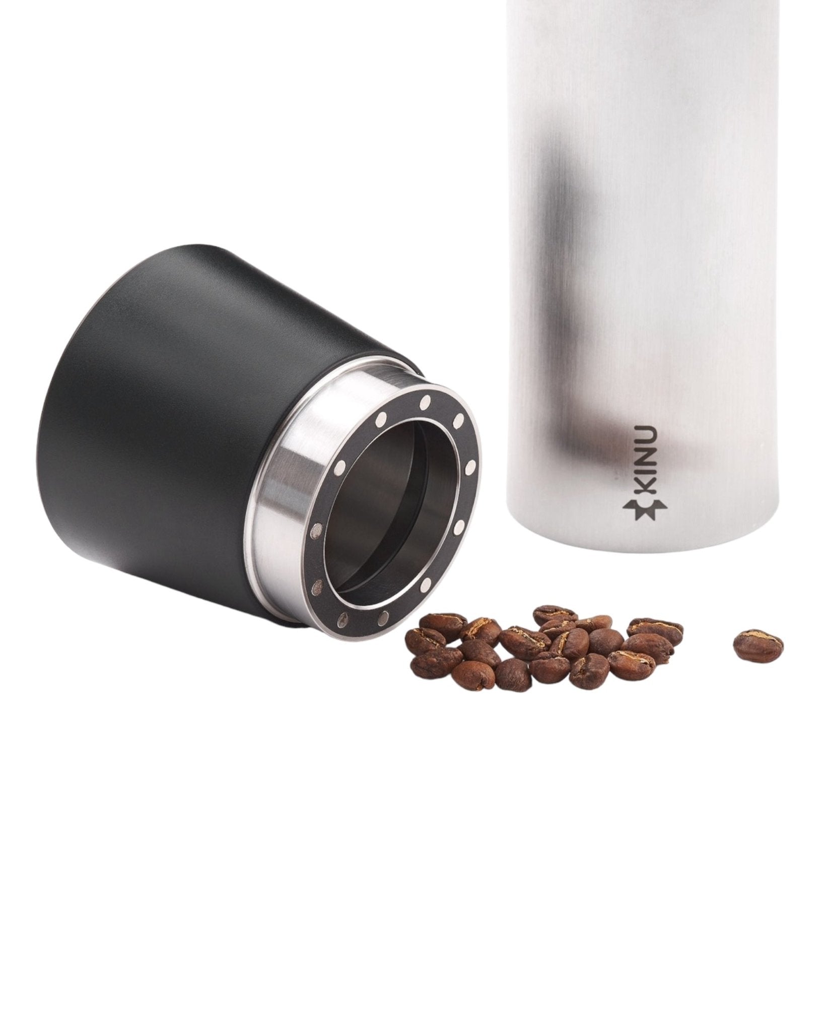 Kinu M47 Classic 2024 manual coffee grinder with detachable black grinding chamber, silver body, and coffee beans scattered nearby, showcasing precision German craftsmanship for optimal coffee grinding experience