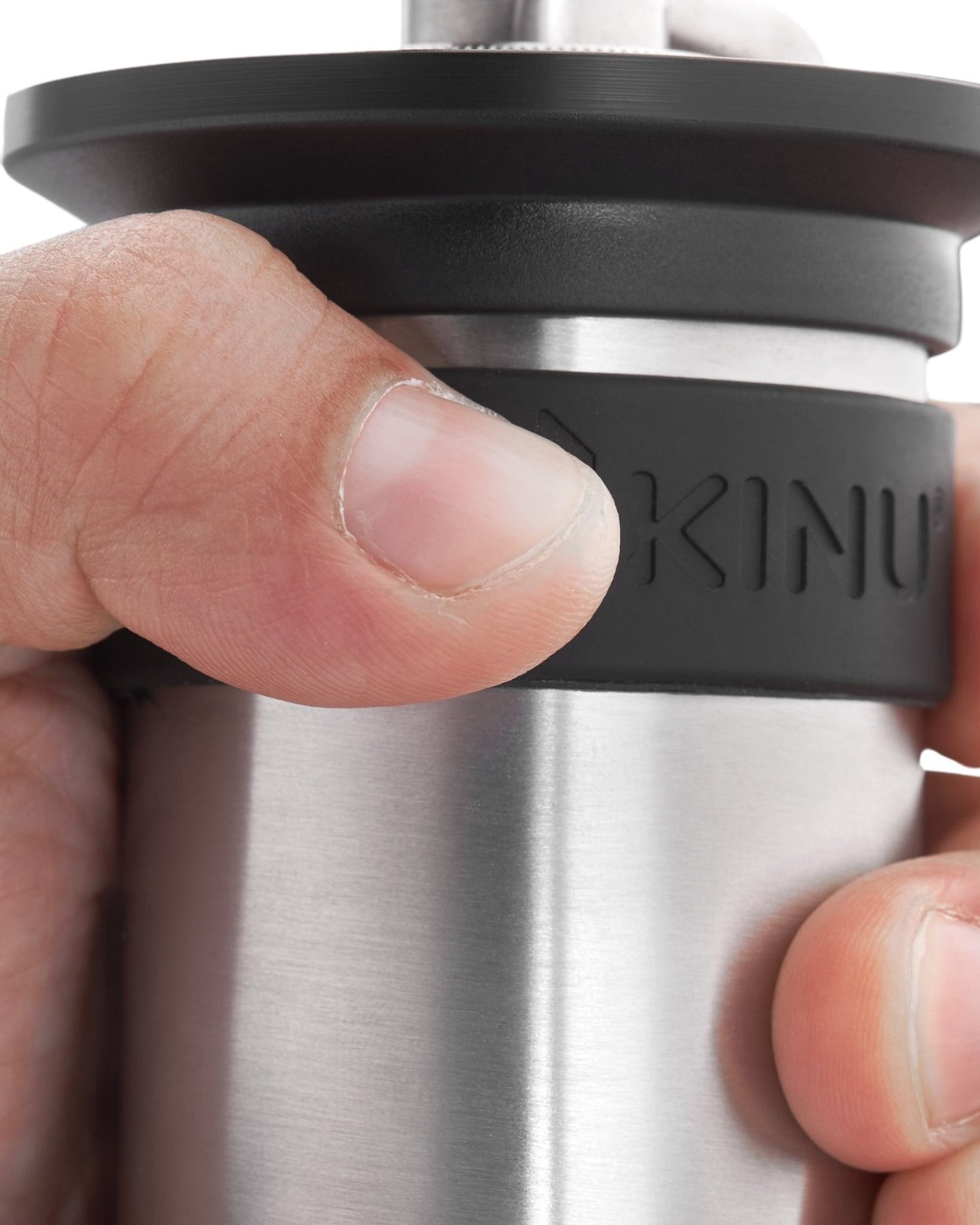 Close-up of Kinu M47 Phoenix manual coffee grinder, showcasing its stainless steel body and precision adjustment ring, held by a hand demonstrating its compact size and ergonomic design for portable, high-quality coffee grinding.