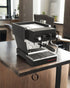 Compact black La Marzocco Linea Micra espresso machine on wooden kitchen counter, featuring chrome accents and pressure gauge