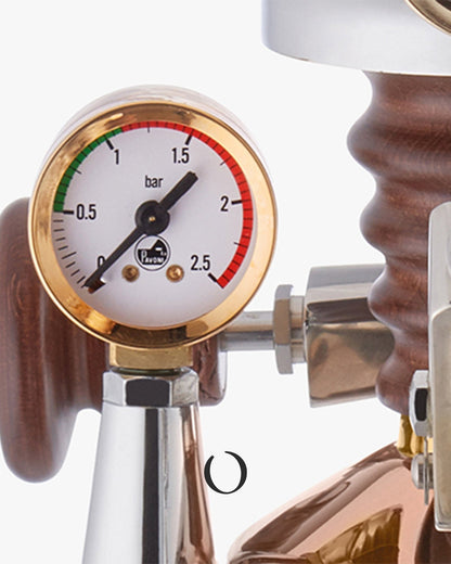 Close-up view of a pressure gauge on a copper-colored espresso machine, showing the dial and part of the machine&