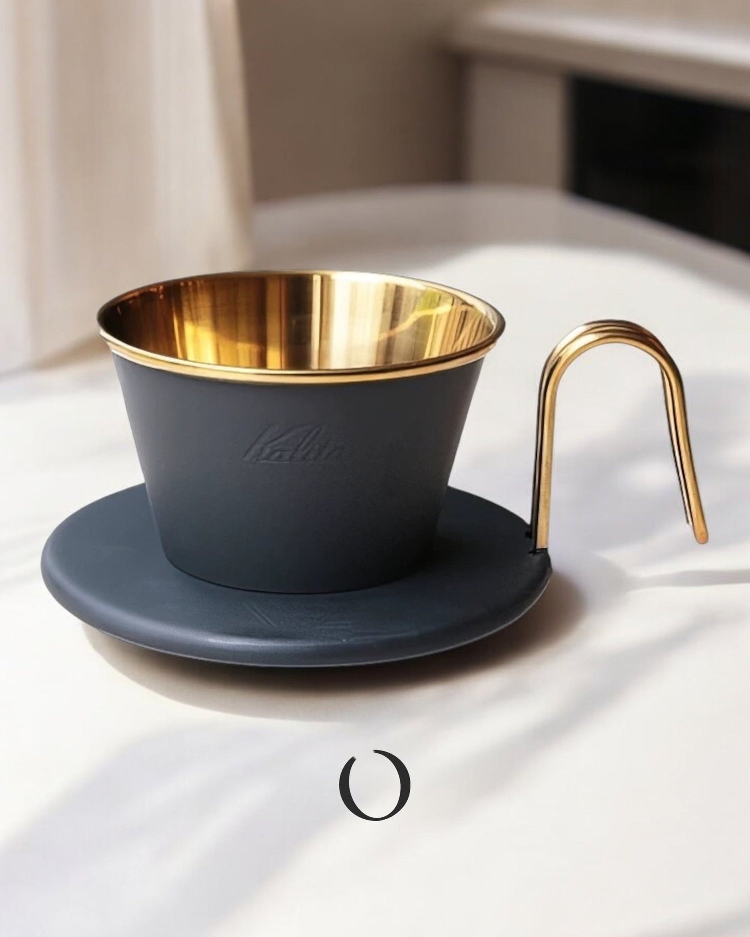 Limited edition Kalita Wave Dripper in black and gold, featuring a sleek matte exterior and shiny gold interior. The coffee dripper sits on a matching black saucer with a gold-colored handle, showcasing elegant design and premium craftsmanship for pour-over coffee brewing.