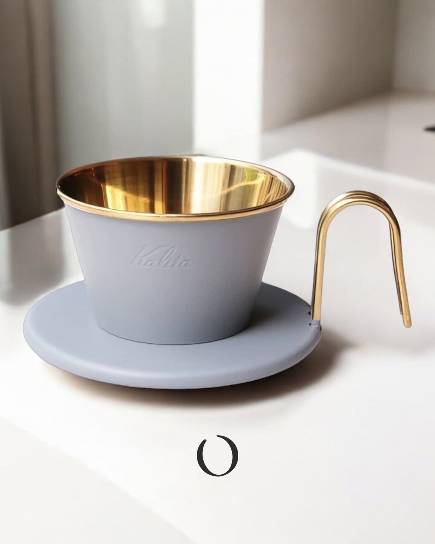 Limited edition Kalita Wave Dripper in light gray with golden interior, featuring a matching saucer and gold-colored handle, showcasing elegant design and premium craftsmanship for pour-over coffee brewing.