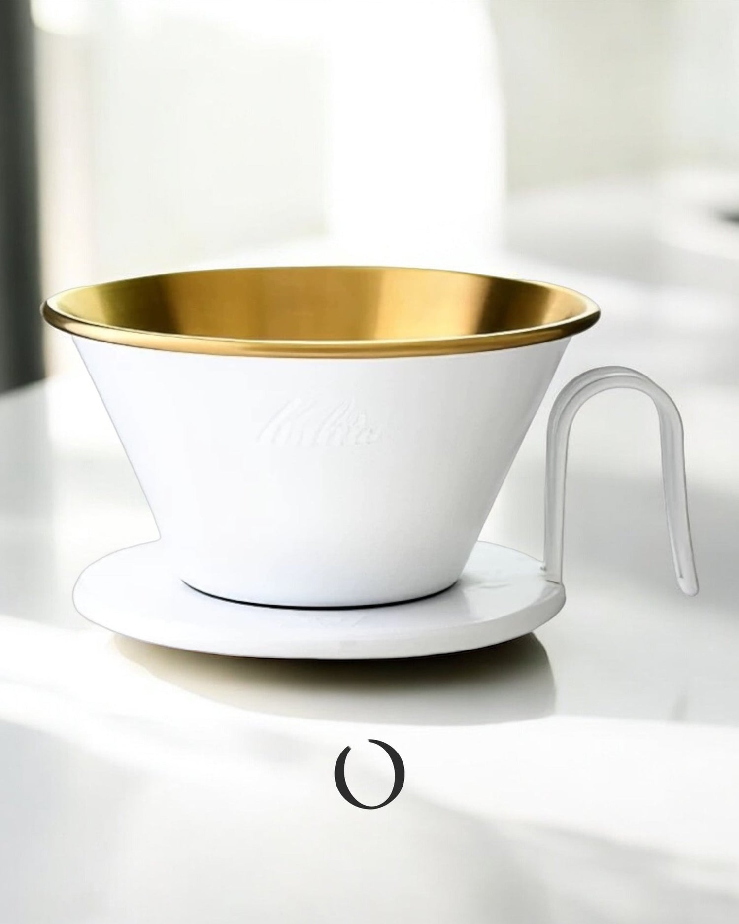 Limited edition Kalita Wave Dripper in white and gold, featuring a conical shape with a flat bottom, three-hole design, and a curved handle, placed on a white surface.