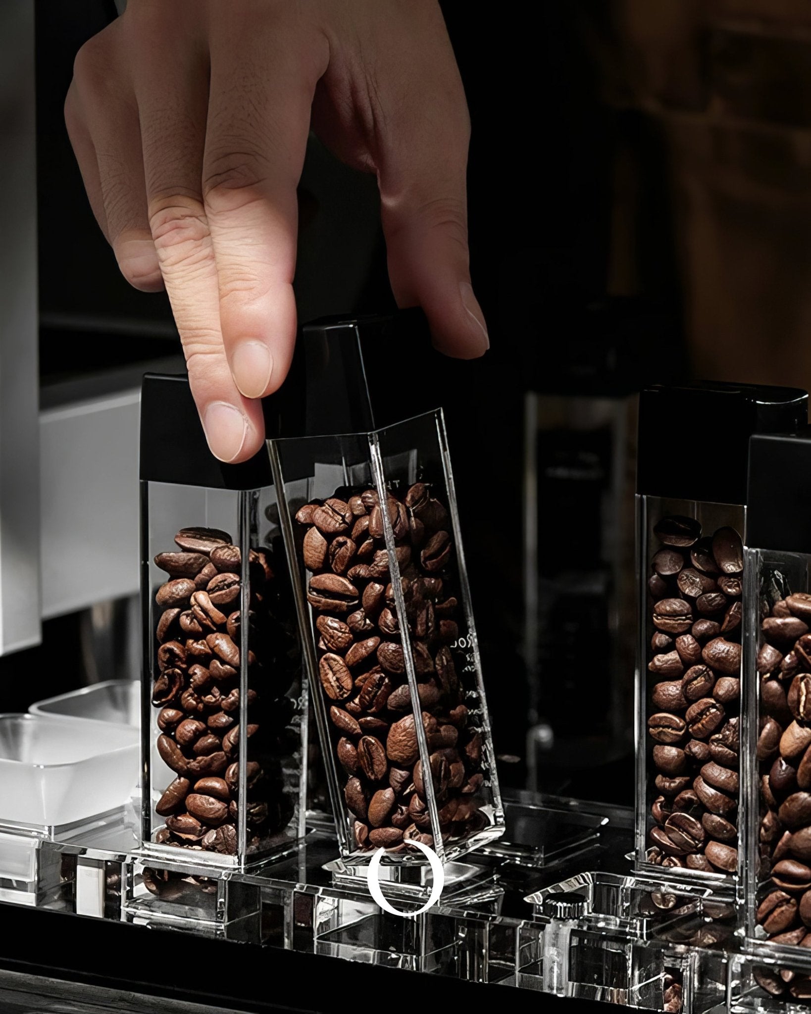 Transparent coffee bean display tubes filled with roasted beans, hand reaching to select one tube from the set, showcasing MUVNA&