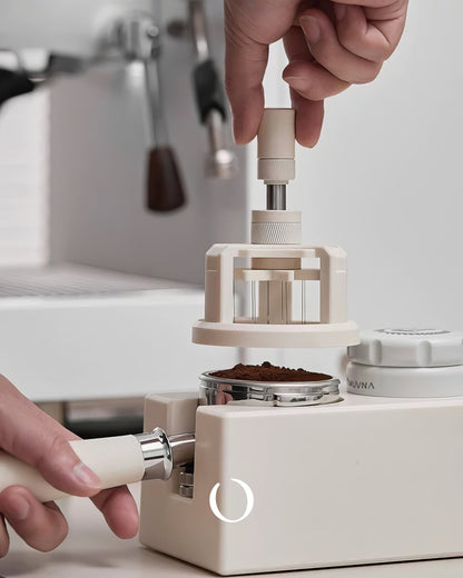 MUVNA Espresso WDT adjustable distribution tool in use, showing hands operating the device to evenly distribute coffee grounds in a portafilter, with espresso machine in background