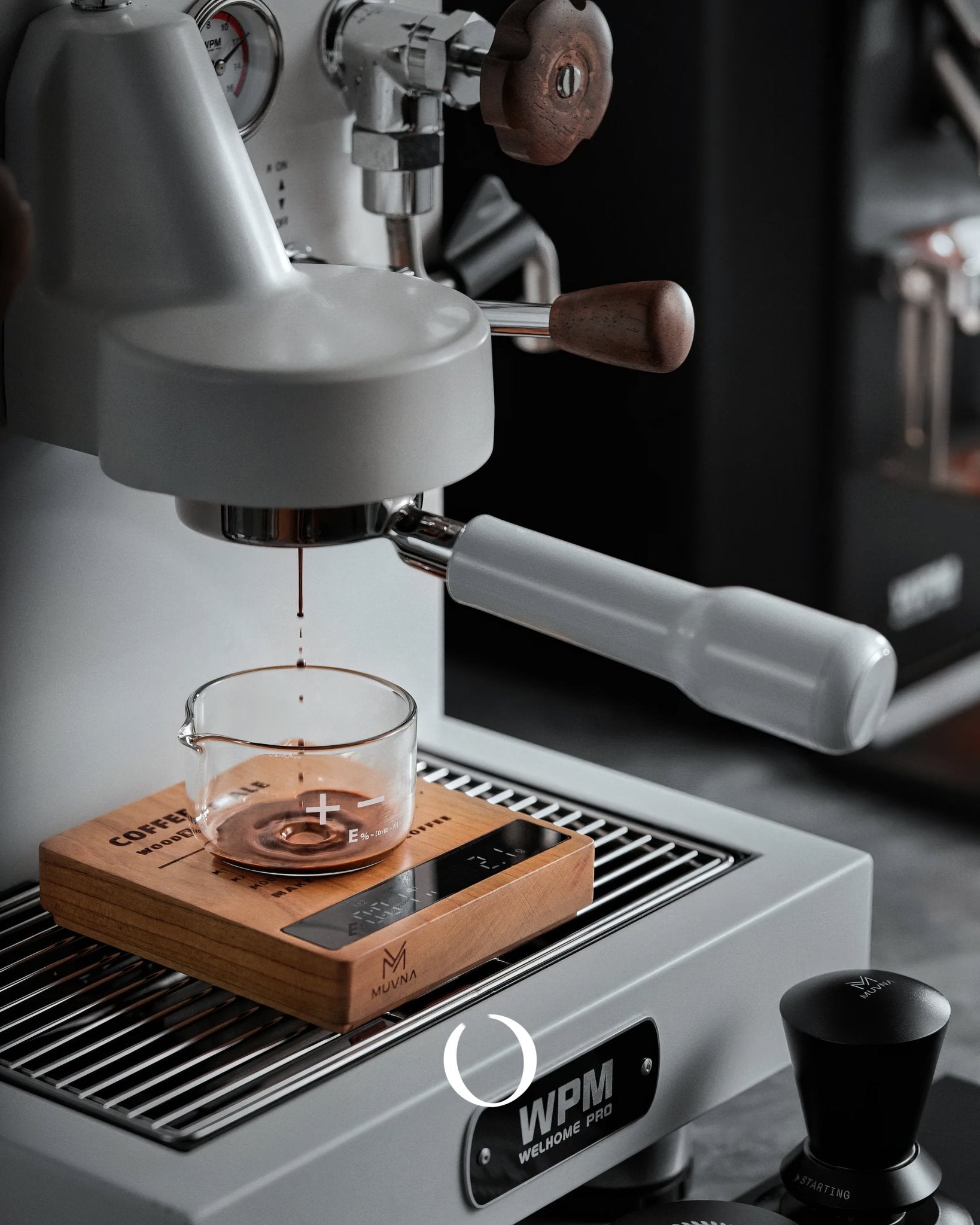 Close-up of espresso machine brewing coffee into a glass cup on a wooden scale, showcasing precision and quality in coffee preparation