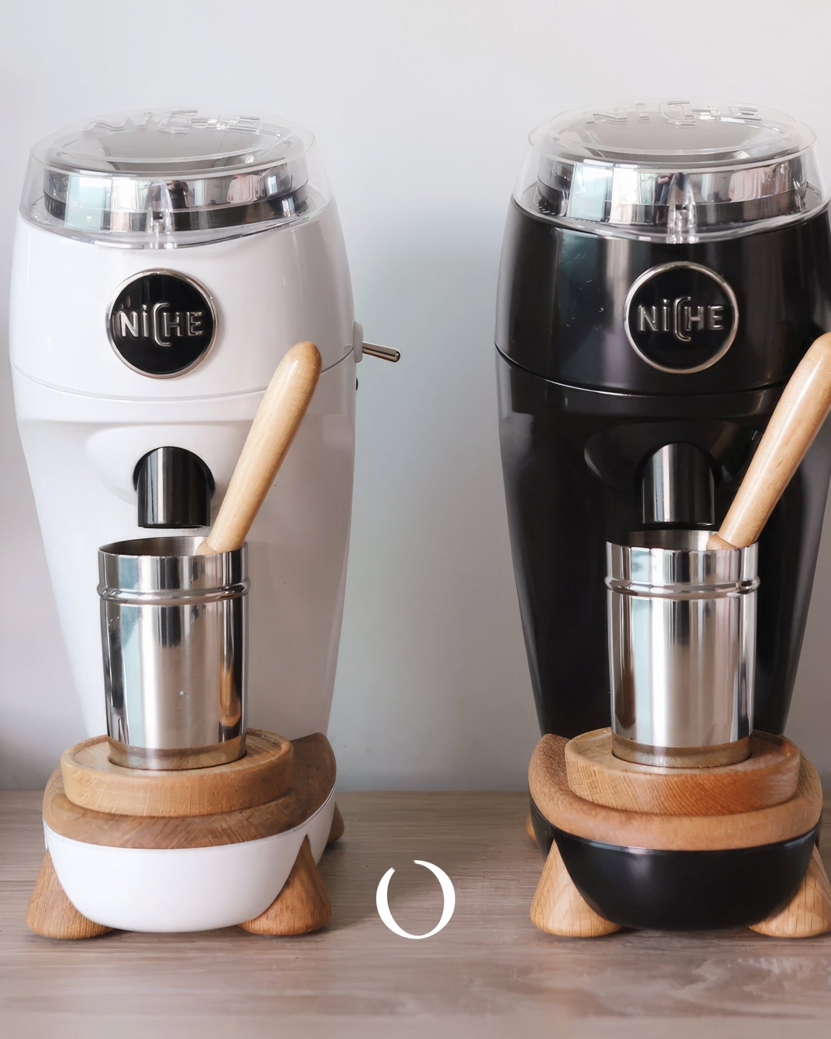 Niche Zero coffee grinders in white and black, featuring sleek aluminum bodies, wooden accents, and stainless steel dosing cups, showcasing professional-grade home espresso equipment with minimalist design