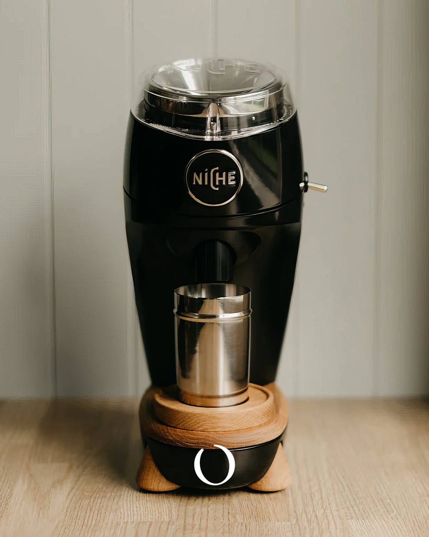 Niche Zero coffee grinder in sleek black design with wooden base, featuring transparent bean hopper and stainless steel grounds cup on wooden countertop