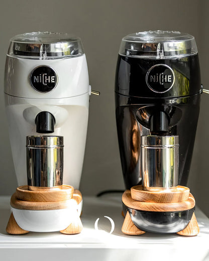 Niche Zero coffee grinders in white and black, featuring sleek design with aluminum body, wood accents, and stainless steel dosing cups, showcasing professional-grade home espresso equipment