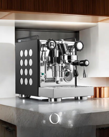 Rocket Appartamento espresso machine with black side panels and circular cutouts, displayed on kitchen countertop, showcasing compact design and professional features for home baristas