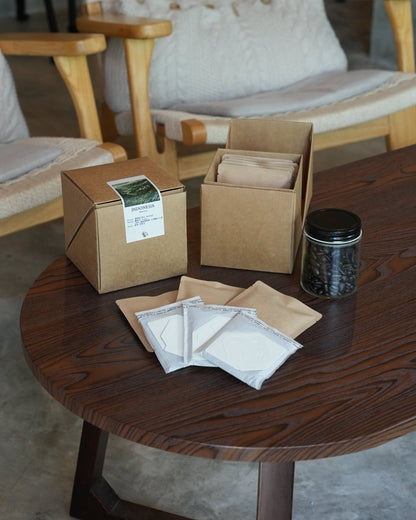 Sumatera coffee product display with kraft boxes, drip bags, and whole beans in jar on wooden table, showcasing packaging and brewing options for ultra dark roast Typica variety