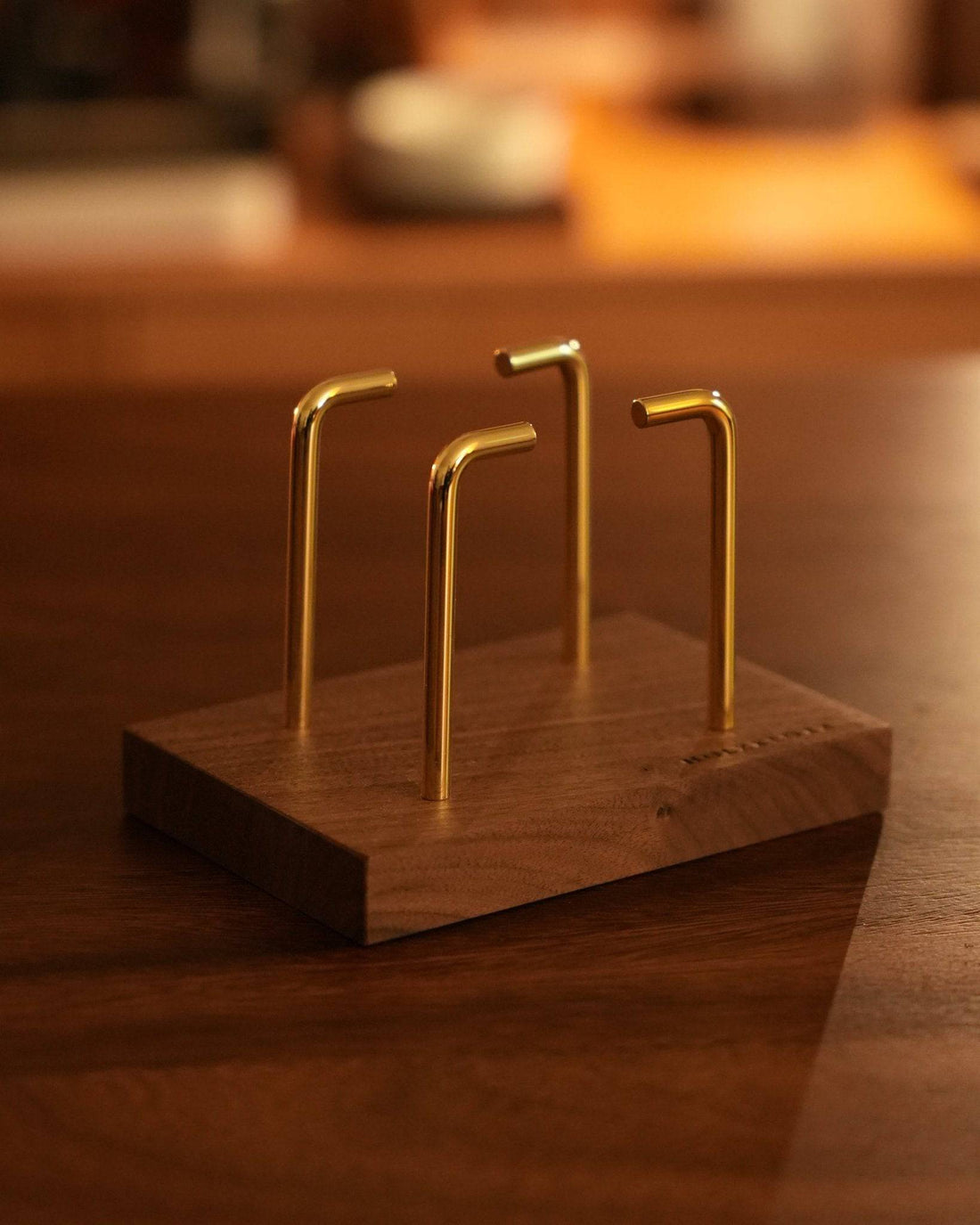 Holzklotz black walnut wood coffee filter stand with golden metal prongs, elegantly displayed on a wooden surface in warm lighting, showcasing its modern and minimalist design for pour-over coffee enthusiasts