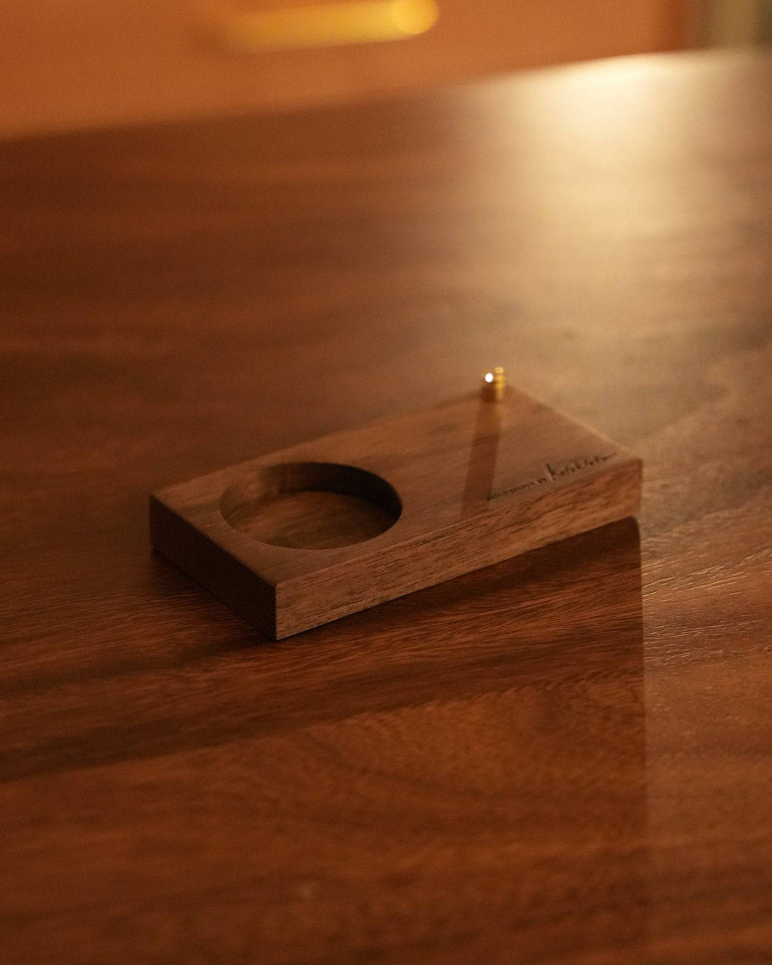 Elegant black walnut wood coffee grinder stand with circular cutout, showcasing rich grain and warm tones under soft lighting on wooden surface