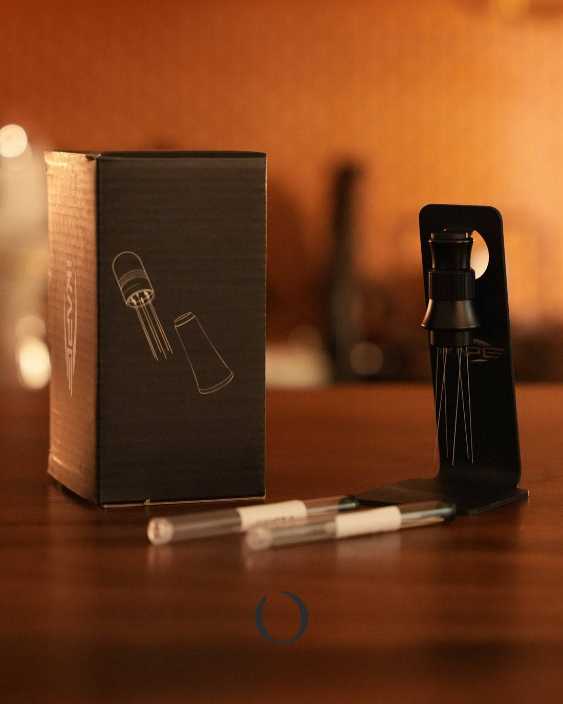 Ikape adjustable espresso distribution tool with magnetic stand, product box, and interchangeable needles for precise coffee ground leveling, displayed on wooden surface in warm lighting