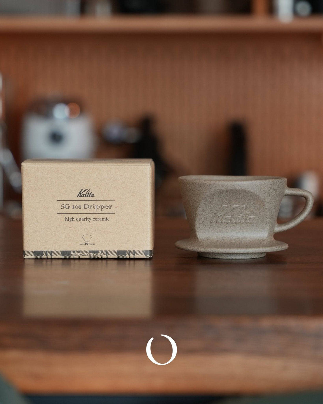 Kalita SG-101 ceramic coffee dripper with packaging box on wooden counter, showcasing high-quality sandstone clay Hasami-yaki craftsmanship for optimal coffee brewing and temperature retention