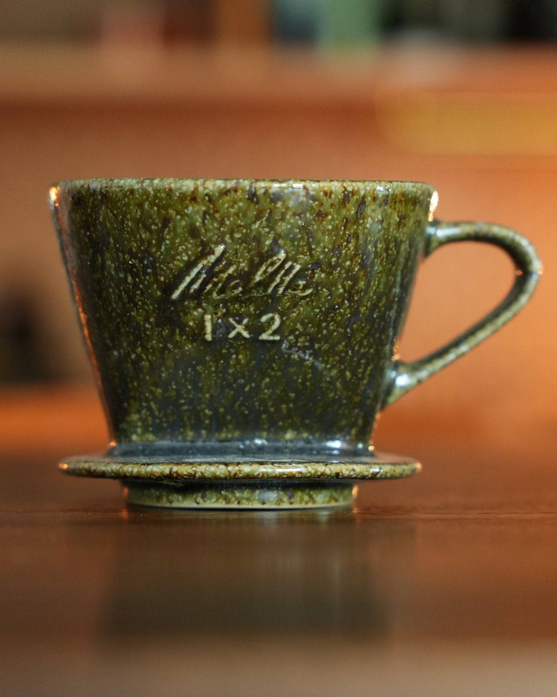 Melitta 1x2 ceramic pour-over coffee dripper in unique yellow-green glaze, showcasing traditional Minoyaki craftsmanship with modern design, placed on wooden surface