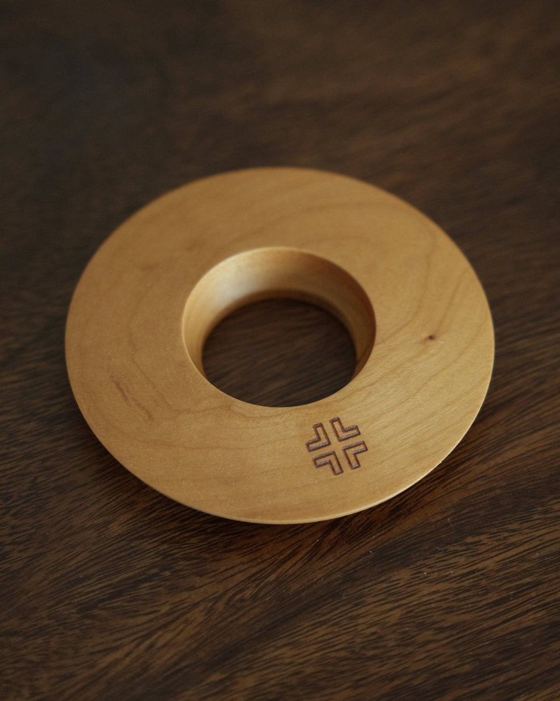 Ninety Plus Coffee Kone Ring 10.1 in cherry wood color, circular wooden base for mini pour-over coffee dripper, featuring a central hole and engraved logo, displayed on dark wood surface