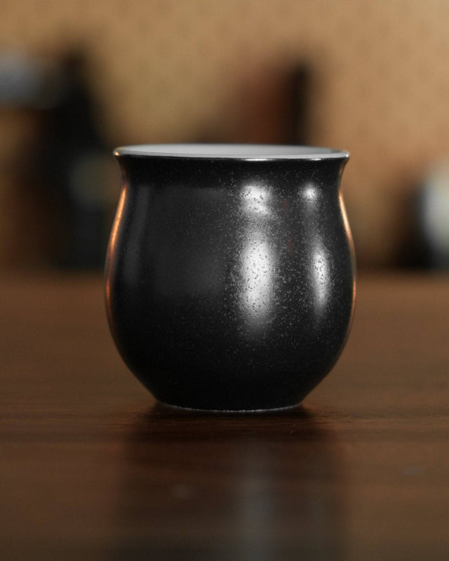 Ninety Plus Coffee Savour Cup 10.1 in obsidian black, curved shape with glossy finish, sitting on wooden surface, designed for premium coffee tasting experience
