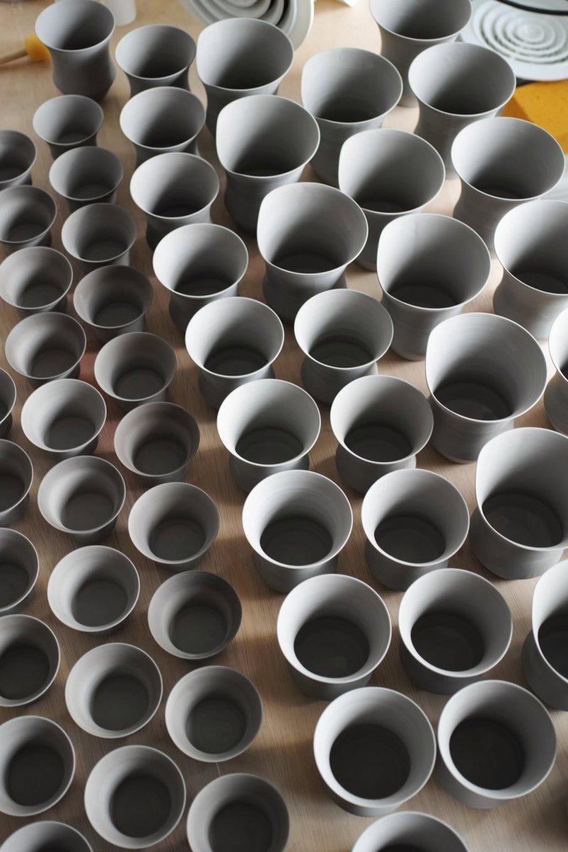Several unglazed cup bodies in different sizes arranged on a workbench, viewed from above