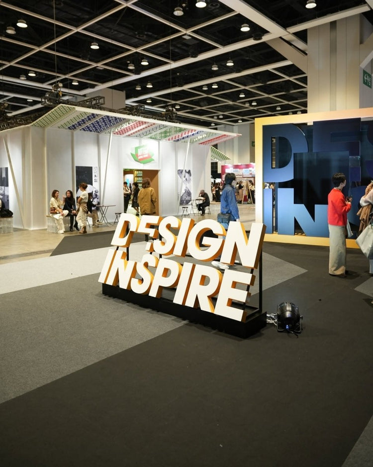 DesignInspire 2025 Venue: There is a large three-dimensional signboard with "DESIGN INSPIRE" on the ground, and behind it are the booths and people flow in the exhibition hall.