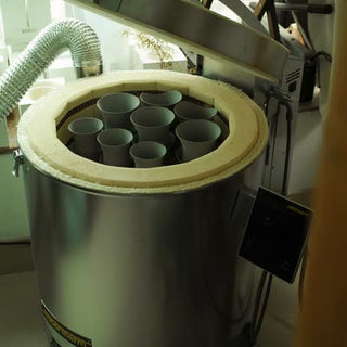 An open large electric kiln filled with unfired Sharing Cup bodies