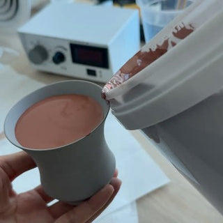 Glaze being poured by hand into an unglazed cup body, filling the inside up to the opening