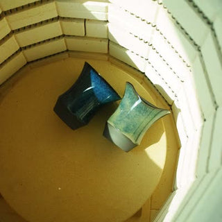 Two blue-glazed Sharing Cup pieces after firing inside an electric kiln with refractory-brick walls