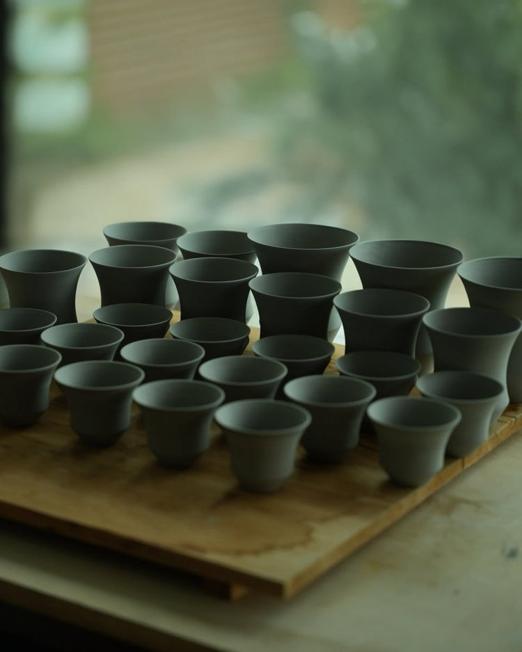 Unglazed Coffee Stage Sharing Cup forms with different heights and rim profiles arranged on a workshop board